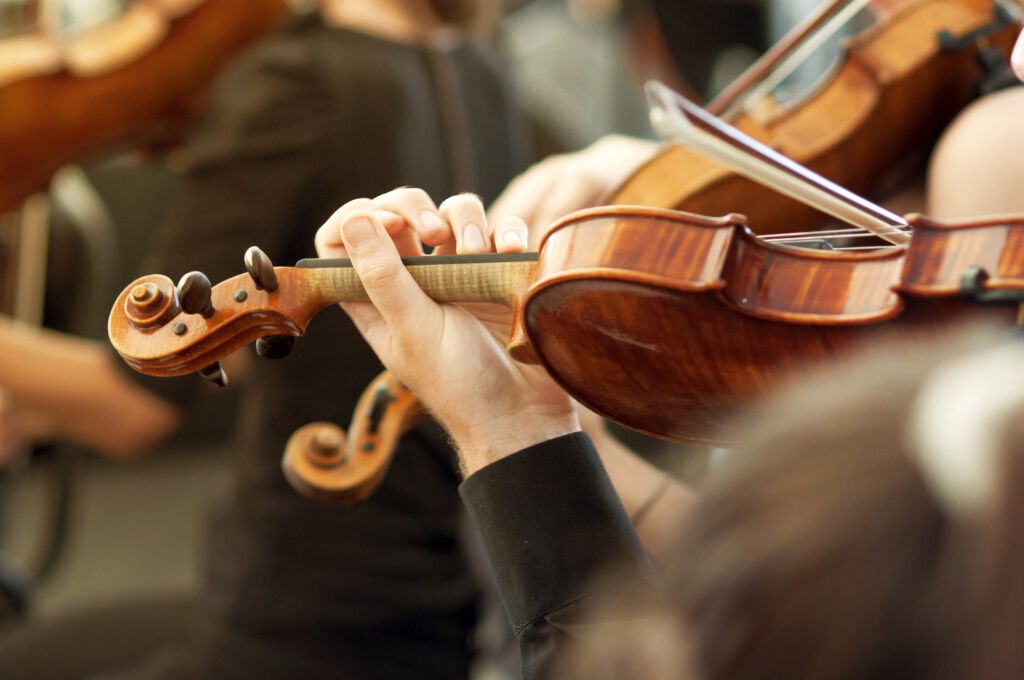 Member of classical music orchestra playing violin on a concert, unrecognizable musician with string instrument, selective focus