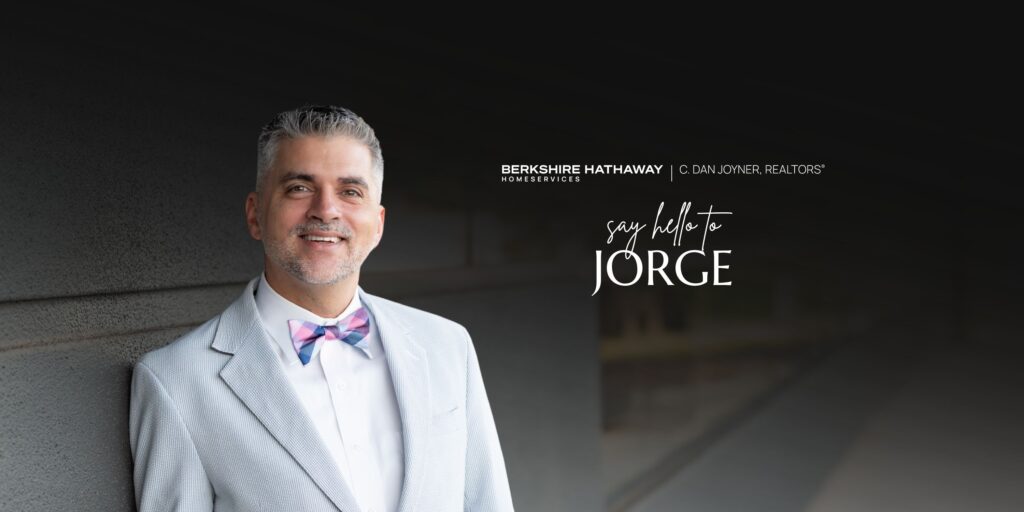 A wide horizontal website banner featuring REALTOR® Jorge Lopez smiling on the left against a dark background. On the right, white text reads 'say hello to JORGE' beneath the Berkshire Hathaway HomeServices C. Dan Joyner, REALTORS® logo.